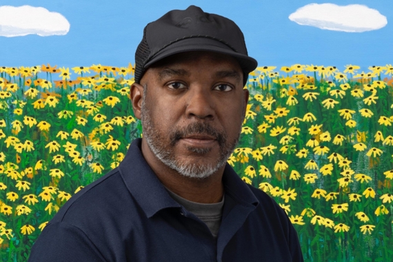 Black man wearing hat against a painted landscape